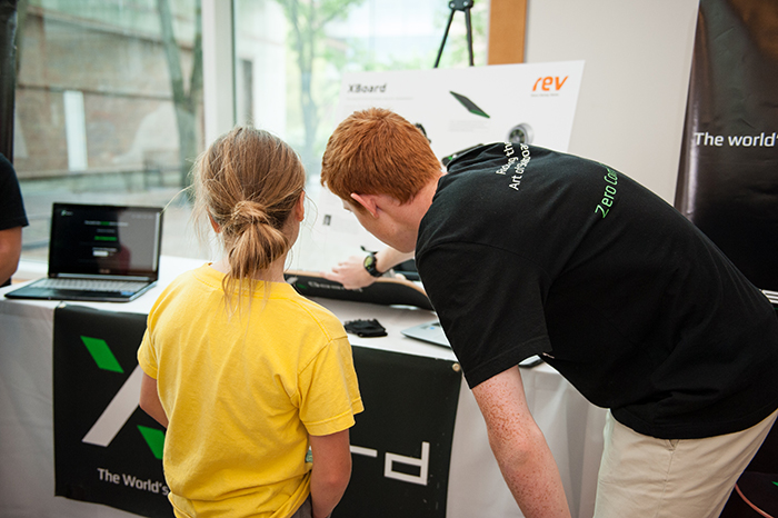 Eric Berg (Cornell ECE '19) shows off XBoard to a young guest.