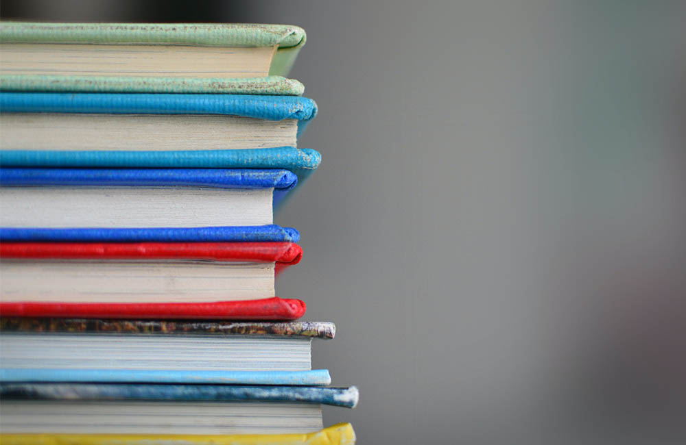 Closeup of a stack of colorful books against a gray out of focus background.