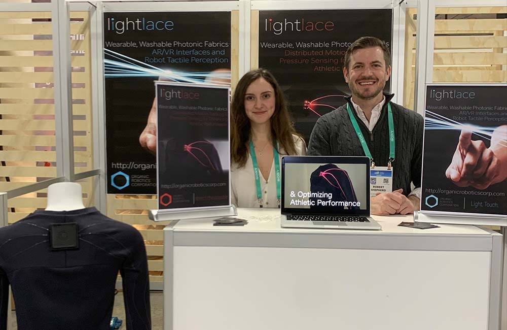 Ilayda Samilgil and Rob Shepherd, co-founders of Organic Robotics Corporation sit at a demo booth showcasing their Light Lace innovation.