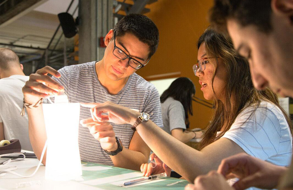 Two students examine the prototype of a light box at Rev.