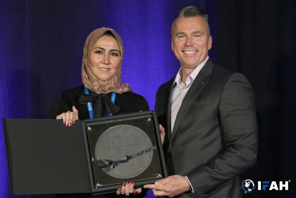 Bayan Alturkestani, founder of Conan MedTech, is holds a plaque acknowledging her as a "Top 100 Healthcare Leader" at the 2021 International Forum on Advancements in Healthcare.