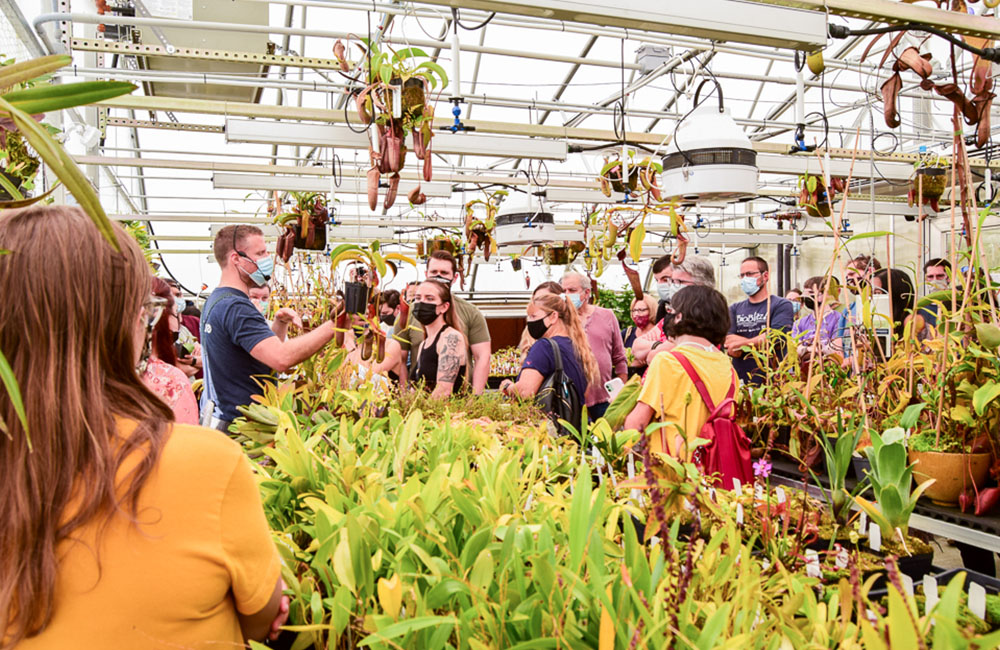 Ryan Georgia of Florae Collaborative leads a tour of Florae's greenhouse. Around him, gathers visitors wearing masks.