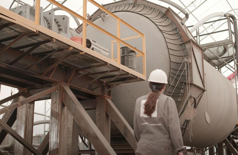 a worker walks in front of a piece of machinery at the Carbon Upcycling plant