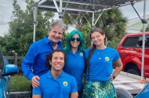 The GismoPower team poses in front of portable photovoltaic deployment technology, which resembles a carport with solar panels.